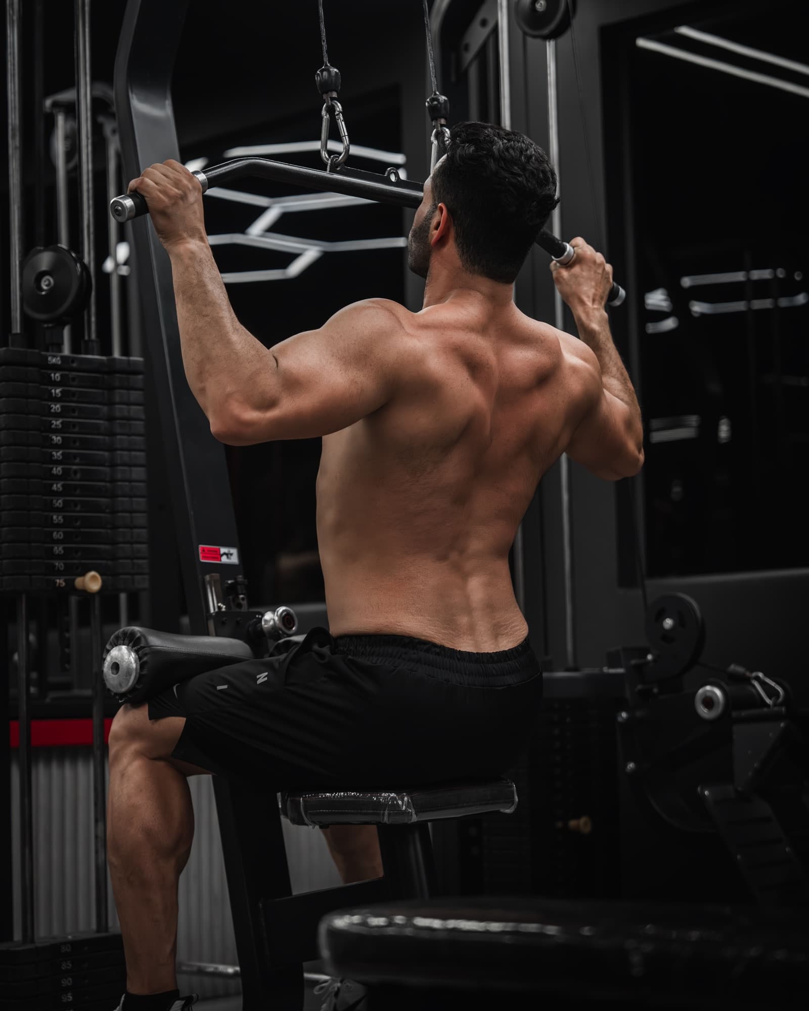 Sportif réalisant un tirage vertical à la poulie haute en salle