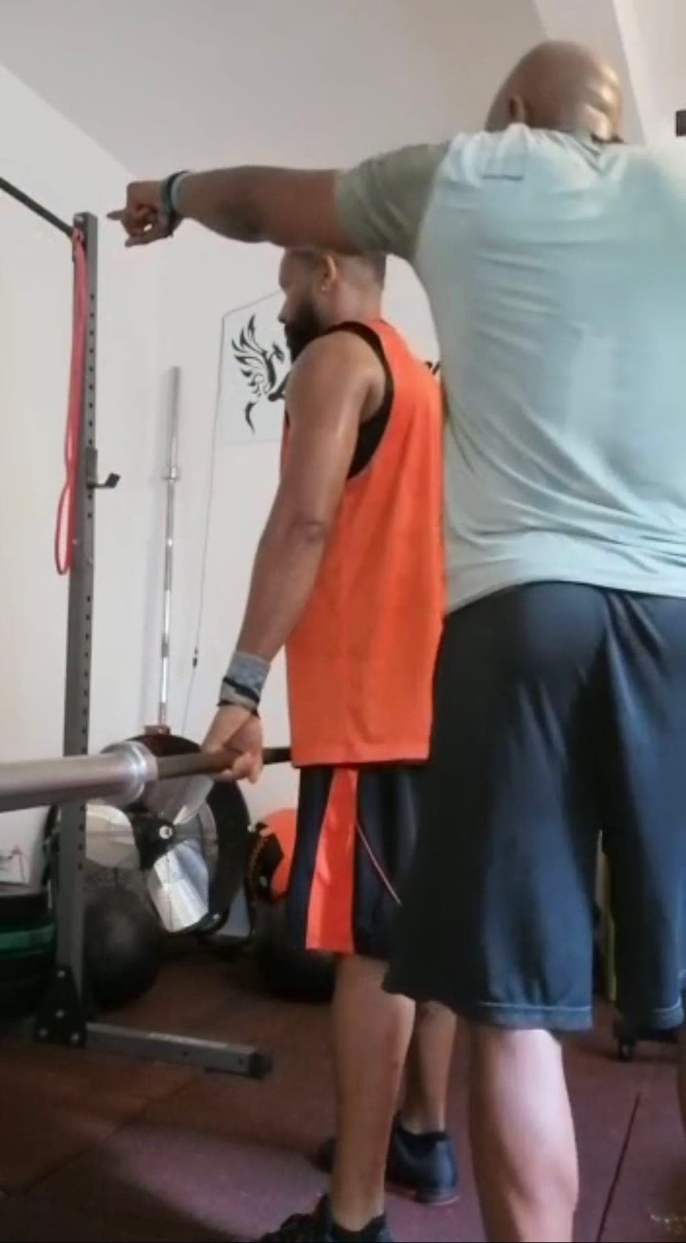 Laurent corrige une position au rack de musculation, barre en main