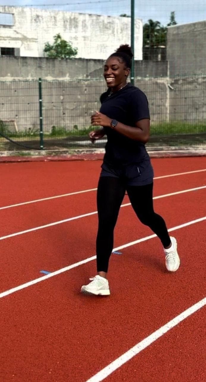 Une sportive accompagnée par Laurent LABECA courant sur une piste d’athlétisme en Guadeloupe